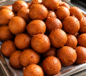 Freshly fried Nigerian puff puff arranged on a tray, featuring a golden, crispy exterior and soft, fluffy interior.